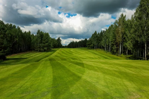 Golfové hřiště, krajina, zelená tráva na pozadí lesa a jasná obloha s mraky — Stock fotografie