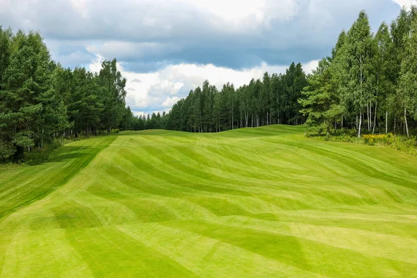 Golf pálya, táj, zöld fű a háttérben egy erdő és egy fényes ég felhők — Stock Fotó