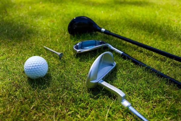 Clubes de golfe e bola jazem na grama verde nos raios do sol eterno — Fotografia de Stock