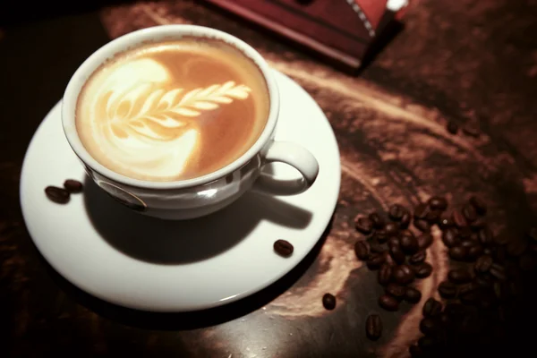 White cup of coffee with beans — Stock Photo, Image