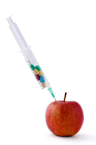 Medyczne strzykawki witn pigułki i czerwone jabłko leżące na biurku, na białym tle — Zdjęcie stockowe