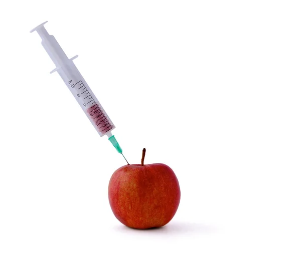 Lékařskou stříkačkou nezdolnou pilulky a červené jablko, ležící na stole, izolovaných na bílém pozadí — Stock fotografie