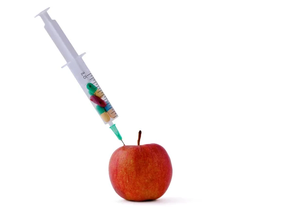 Medyczne strzykawki witn pigułki i czerwone jabłko leżące na biurku, na białym tle — Zdjęcie stockowe