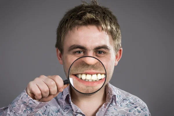 Mann mit Lupe, die Zähne zeigt — Stockfoto