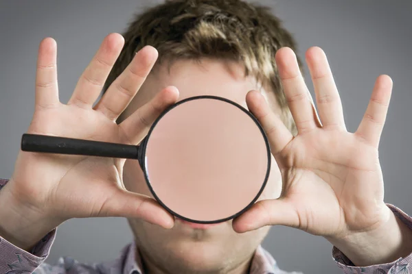Man with magnifying glass showing teeth — Stock Photo, Image