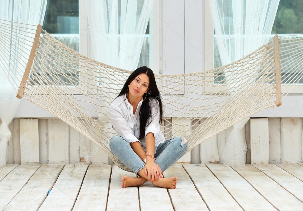 Beautiful smiling  young woman relaxing in hammock at home