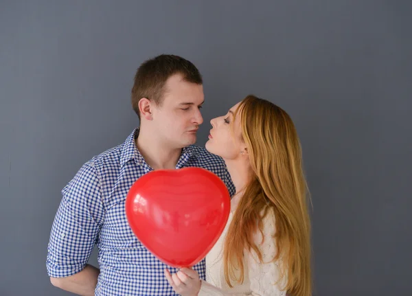 Nádherný pár v lásce s červeným balónkem tvaru srdce pro den svatého Valentýna, na šedém pozadí — Stock fotografie