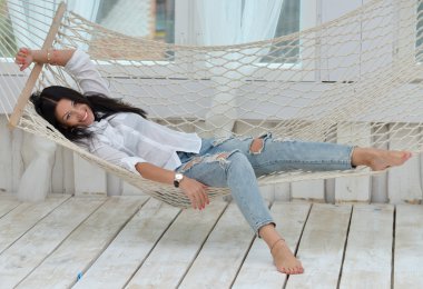 Güzel gülümseyen genç kadın evde hamakta rahatlatıcı