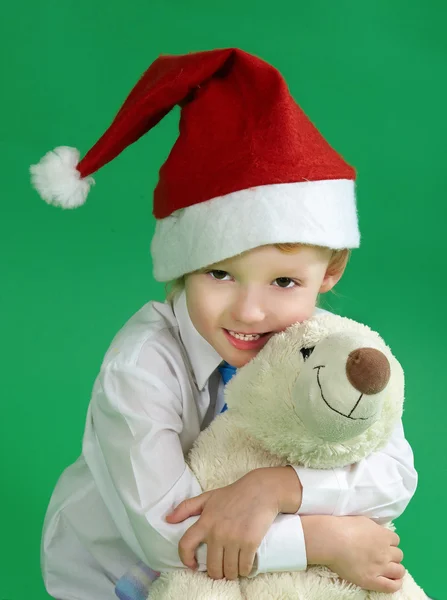 Niño vistiendo un sombrero de Navidad y sosteniendo juguete, fondo verde —  Fotos de Stock