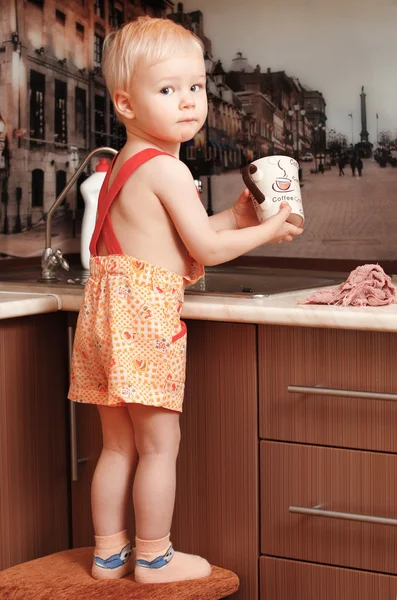 Portrait of a child holding a cup at the kitchen — Stock Photo, Image