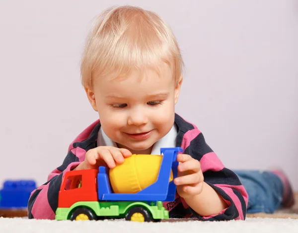 Niño sentado en el suelo y jugando con juguetes, fondo verde —  Fotos de Stock