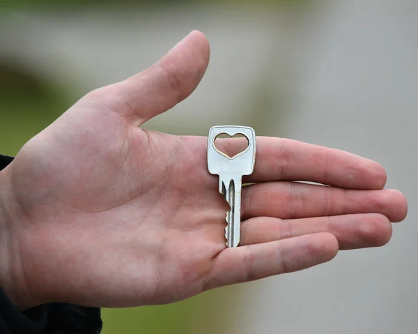 Χέρι που κρατά το κλειδί που απομονώνονται σε γκρι φόντο — Φωτογραφία Αρχείου