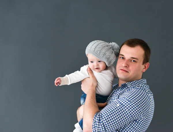 Szczęśliwy ojciec prowadzenia syna na białym tle na szarym tle — Zdjęcie stockowe