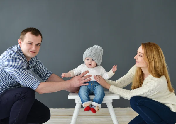 Szczęśliwa młoda para z małych dziecka, usytuowanie na ciemnym tle — Zdjęcie stockowe