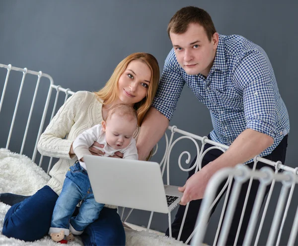 Mãe, pai com bebê e laptop sentado na cama em casa — Fotografia de Stock