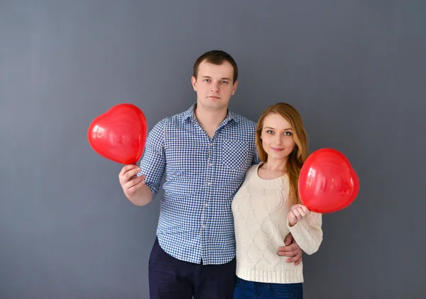Vackra par i kärlek med röd ballong hjärta form för alla hjärtans dag, på grå bakgrund — Stockfoto