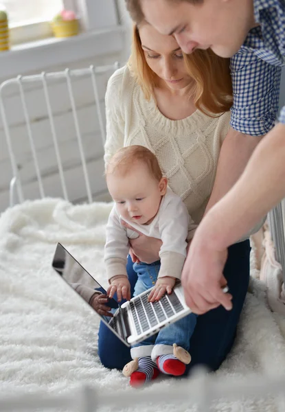 Mother ,father with baby and laptop sitting on bed at home — Stock Photo, Image