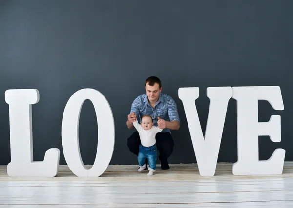 Happy father carrying son isolated on gray background near large letters of the word love