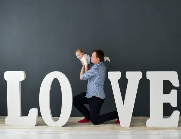 Happy father carrying son isolated on gray background near large letters of the word love — Stock Photo, Image