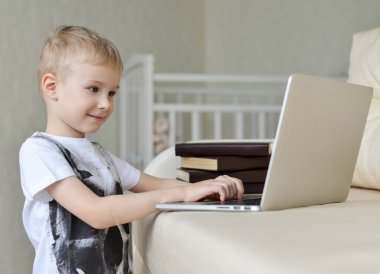 Küçük çocuk ile laptop evde kanepede oturan