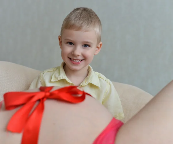 Zwangere moeder met haar schattige kleine jongen op de Bank — Stockfoto