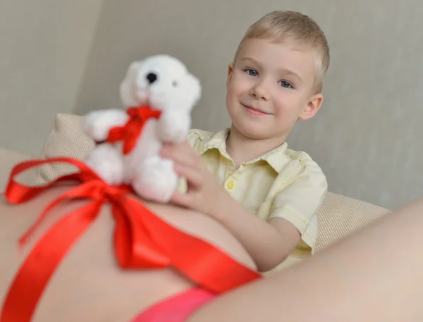 Zwangere moeder met haar schattige kleine jongen op de Bank — Stockfoto