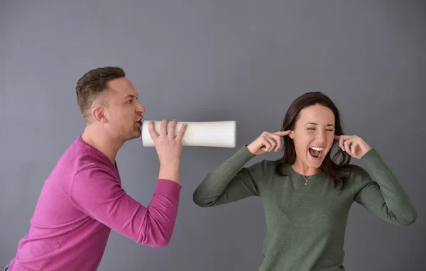 stock image Man talking through  tube and a woman plugging her ears