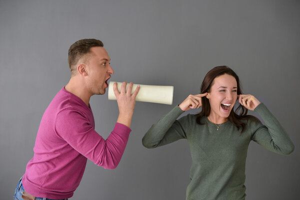 Man talking through  tube and a woman plugging her ears
