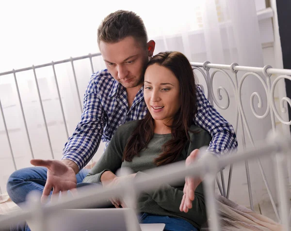 Young couple using a laptop lying on their bed — Stock Photo, Image