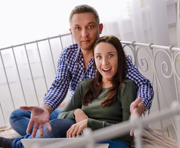 Young couple using a laptop lying on their bed — Stock Photo, Image