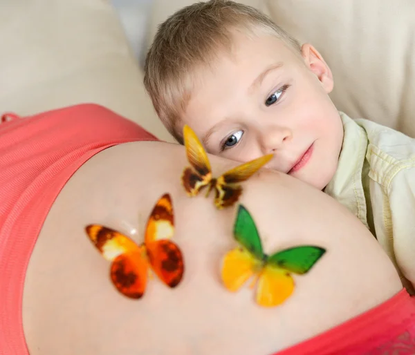 Pregnant mother with her cute little boy on the sofa — Stock Photo, Image