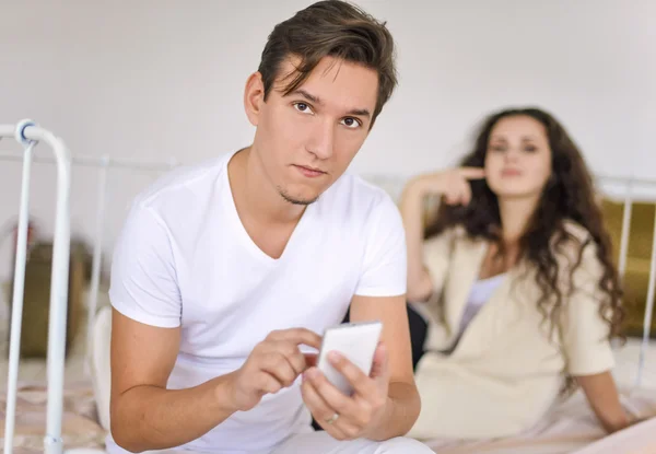 Csinos fiatal pár az ágyban - aggódó barátja mobiltelefonon beszél — Stock Fotó
