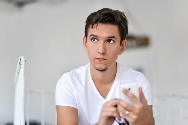 Hombre joven en el dormitorio usando el teléfono celular — Foto de Stock