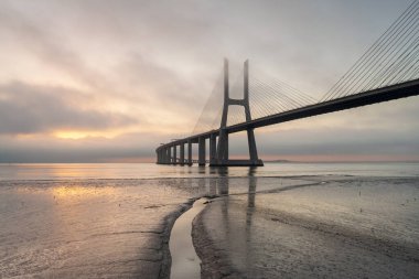 Lizbon Köprüsü 'nde renkli gündoğumu olan bir arka plan. Vasco da Gama Köprüsü bir dönüm noktasıdır ve dünyanın en uzun köprülerinden biridir. Şehir manzarası. Portekiz inanılmaz bir turistik yerdir.. 