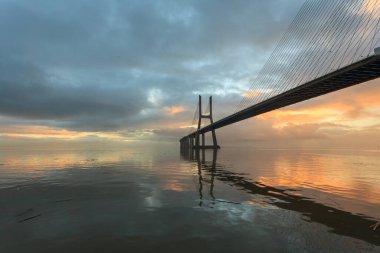 Lizbon Köprüsü 'nde renkli gündoğumu olan bir arka plan. Vasco da Gama Köprüsü bir dönüm noktasıdır ve dünyanın en uzun köprülerinden biridir. Şehir manzarası. Portekiz inanılmaz bir turistik yerdir.. 