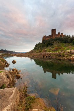 Almourol Kalesi 'nde gün batımı, Portekiz' de Tagus Nehri. Gün batımında, kırmızı bulutların altındaki kale duvarlarıyla muhteşem bir manzara. Güzel Landmark bir tatil beldesidir..