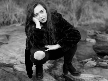 Tarlada çömelmiş genç bir kadın.