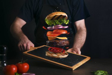 Adam servis masasında lezzetli bir hamburger servis ediyor.