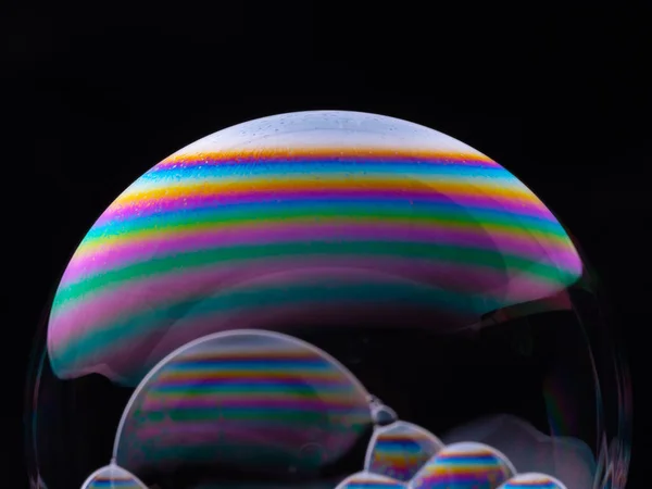 Große Seifenblasen mit Regenbogengradienten isoliert auf schwarzem Hintergrund. Makroaufnahme in Großaufnahme. — Stockfoto