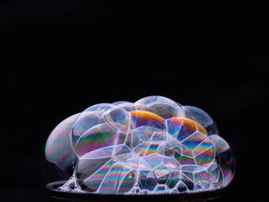 Gökkuşağı eğimli köpük baloncuklarından soyut desen. Sabun köpükleri siyah arkaplanda izole edilmiş. Makro çekim.