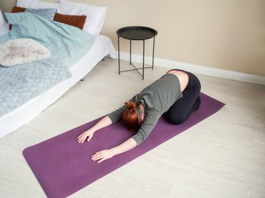 Yoga minderinde asana yapan bir kadın. Yatak odasında esneme egzersizleri. Evde antrenman. Sağlıklı yaşam tarzı kavramı.