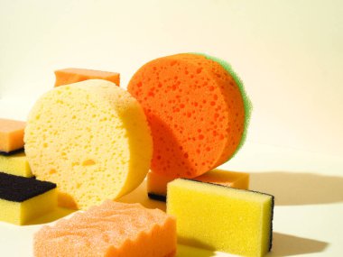 Kauçuk süngerli kompozisyon. Yuvarlak ve dikdörtgen şekiller. Sarı arka plan. Soyut kompozisyon. Farklı süngerler. Sert gölge biçimi.