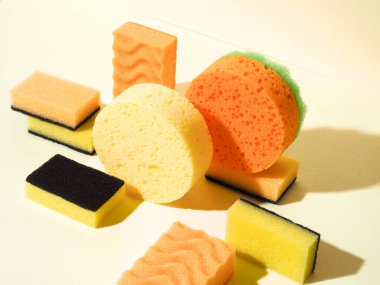 Kauçuk süngerli geometrik kompozisyon. Yukarıdan aşağı açılı bir fotoğraf. Sarı arka plan. Soyut model. Sert gölgeli farklı süngerler.