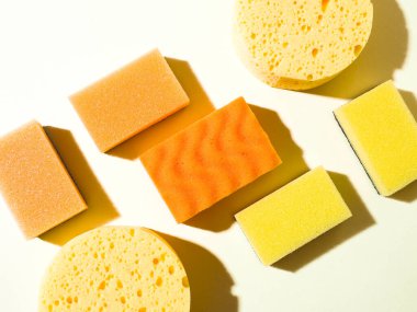 Yuvarlak ve dikdörtgen plastik süngerler. Soyut geometrik bileşim. Sarı arka plan. Temizlik hizmeti konsepti. Sert gölgeler.