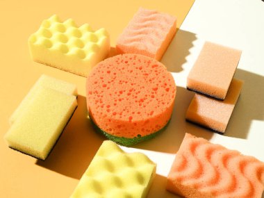 Yuvarlak ve dikdörtgen plastik süngerlerin deseni. Soyut geometrik bileşim. Sarı ve turuncu arka plan. Temizlik hizmeti kavramı.