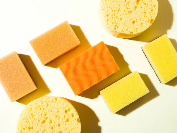 Yuvarlak ve dikdörtgen plastik süngerler. Soyut geometrik bileşim. Sarı arka plan. Temizlik hizmeti konsepti. Sert gölgeler.