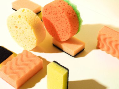 Farklı şekillerde sünger süngerler. Manzarayı kapat. Sarı arka plan. Sert gölge. Temizlik hizmeti kavramı.