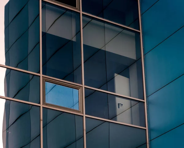 青いパネルと黄色の窓枠を持つオフィスビルのファサードのミラー窓家の歪んだ反射で — ストック写真