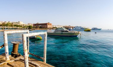 Kızıl denizin arka planında plaj şemsiyeleri ve palmiye ağaçları ve Mısır hurghada 'da gemiler.