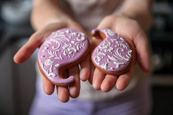 Pembe kremalı zencefilli kurabiyeler ve kadın ellerinde yakın plan desenler.